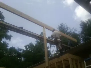 Carpenter setting a ridge beam over a new addition frame — Ice Dam Removal by Roofing Brothers in Archbald