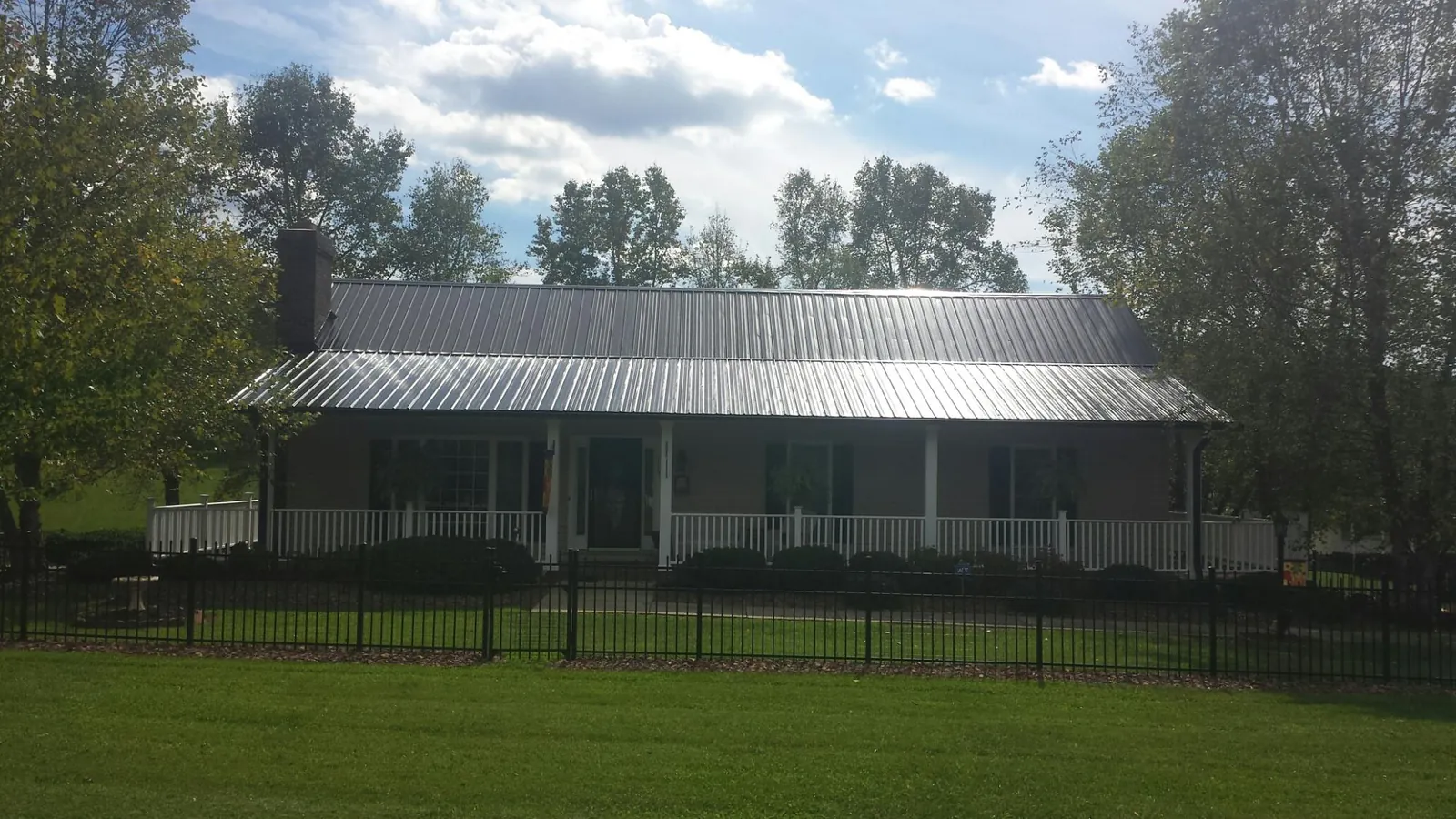 Gray metal roof on a brick ranch with a full width front porch — Gutter Guard Installation work by our crew in Archbald