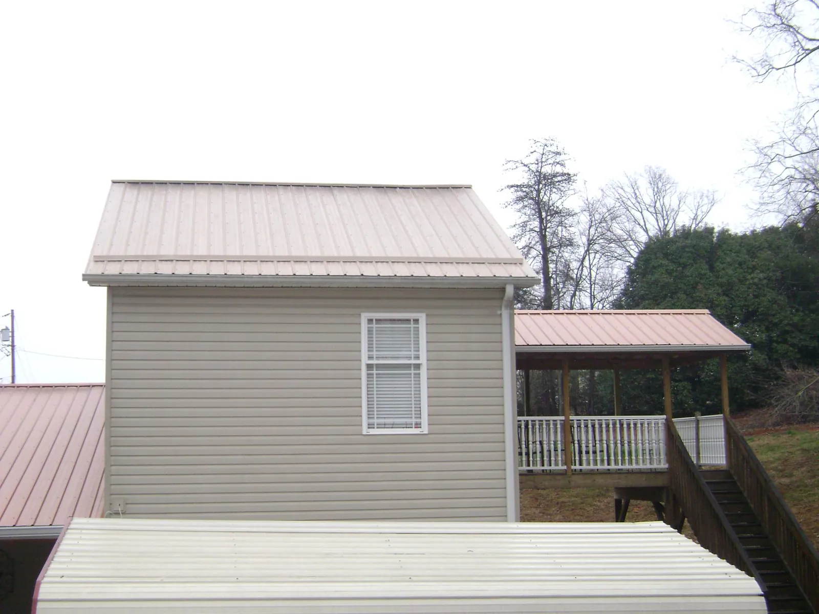 Tan metal roofs on a two story addition and attached porch, from a Roof Replacement job in Archbald