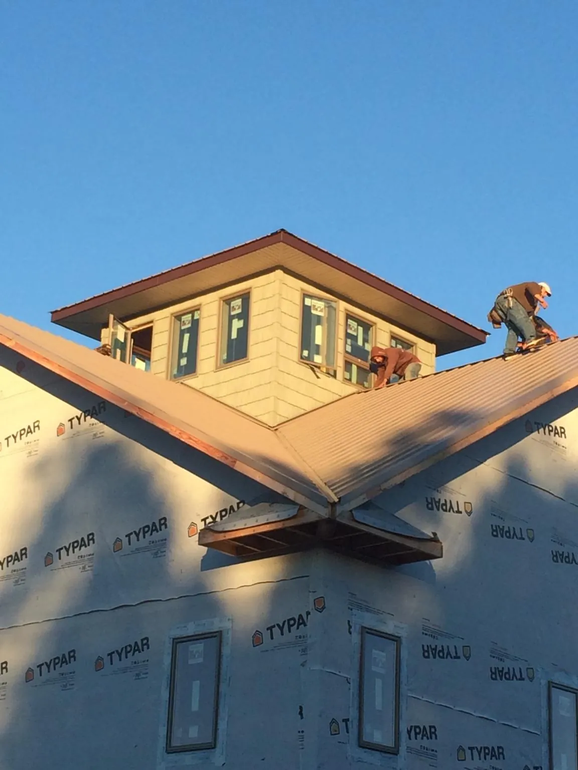 Roofers working around a rooftop cupola on a new metal roof at sunset — Roof Waterproofing in Archbald by Roofing Brothers